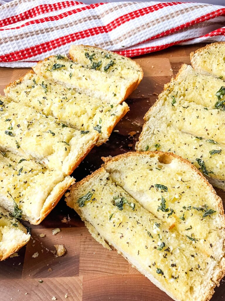 Fresh garlic bread sliced on a cutting board.