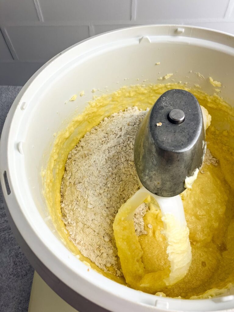 Dry ingredients are added to the wet ingredients in a stand mixer bowl.
