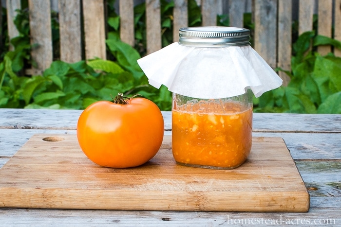 Jar of tomato pulp next to a yellow tomato.