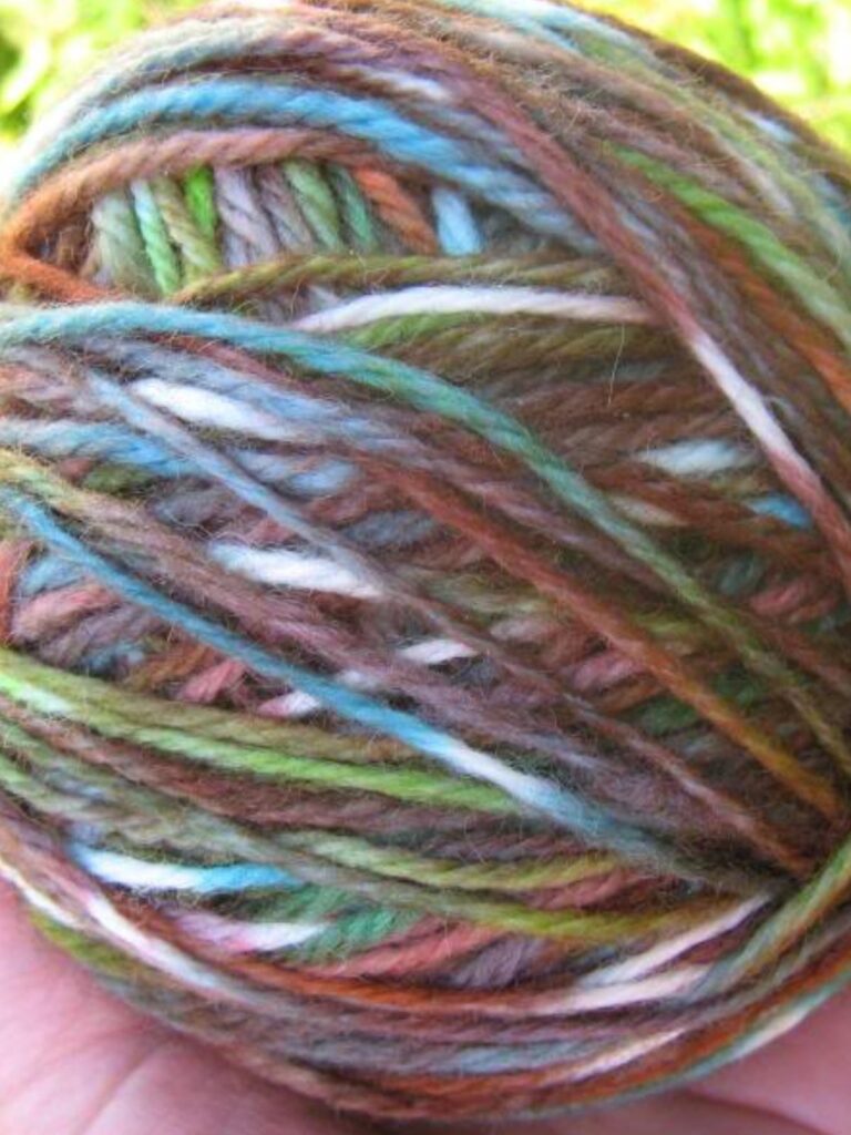A hand holding a ball of yarn that was dyed with Kool-Aid.