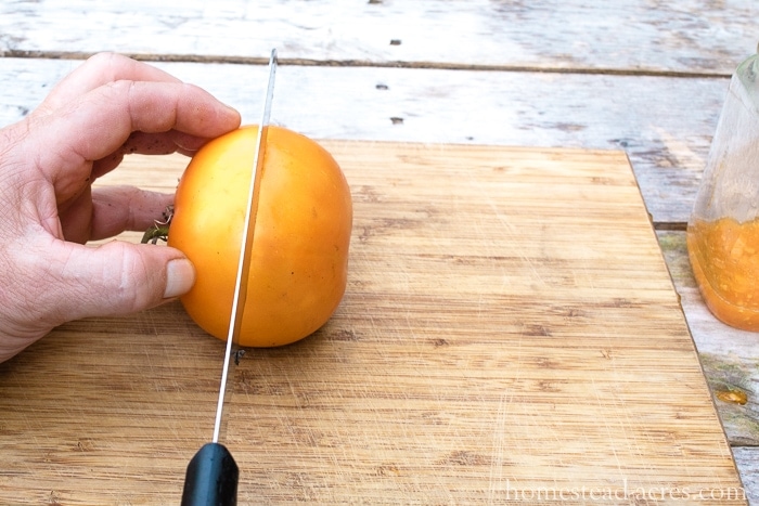 Cutting a yellow tomato in half.