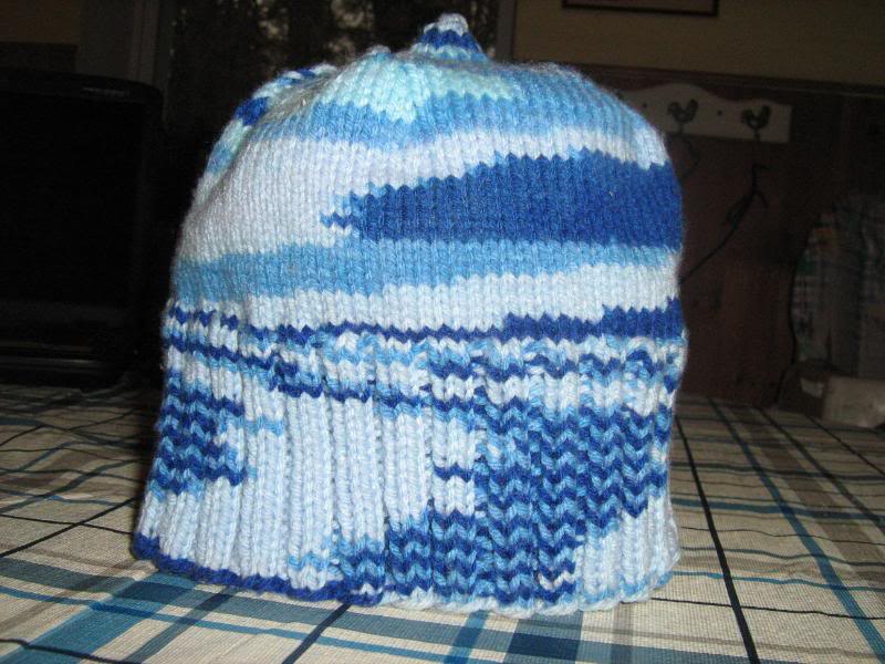Knitted blue baby hat standing up on a table.