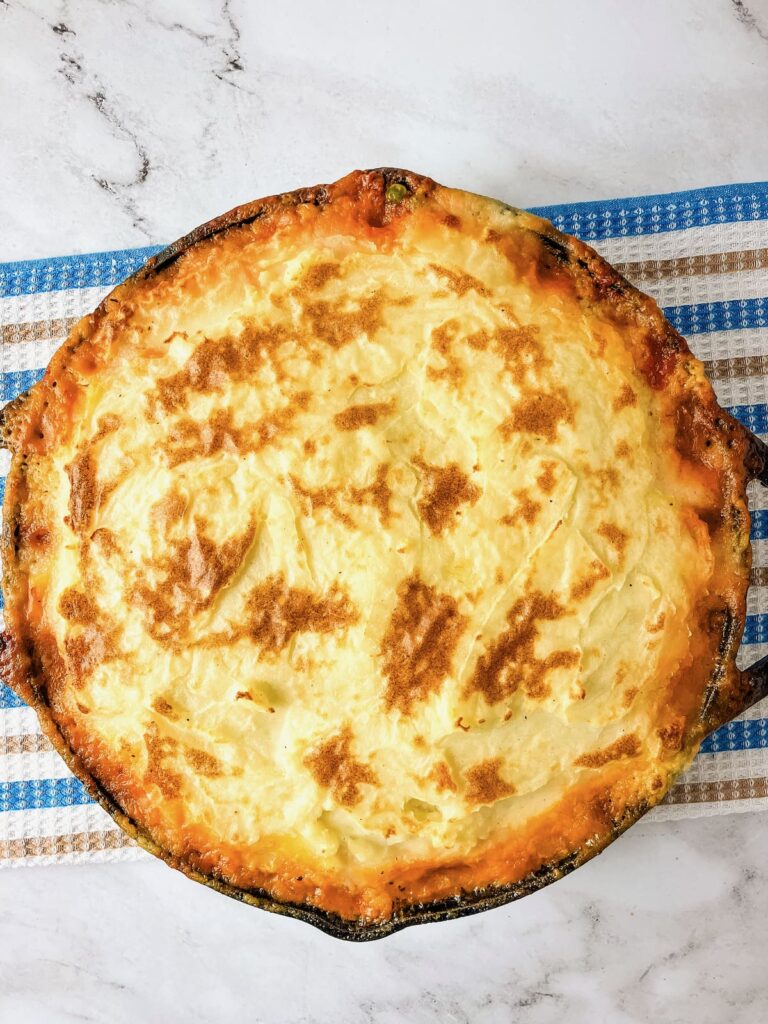 Homemade Shepherd's pie cooling after baking in a cast iron skillet.