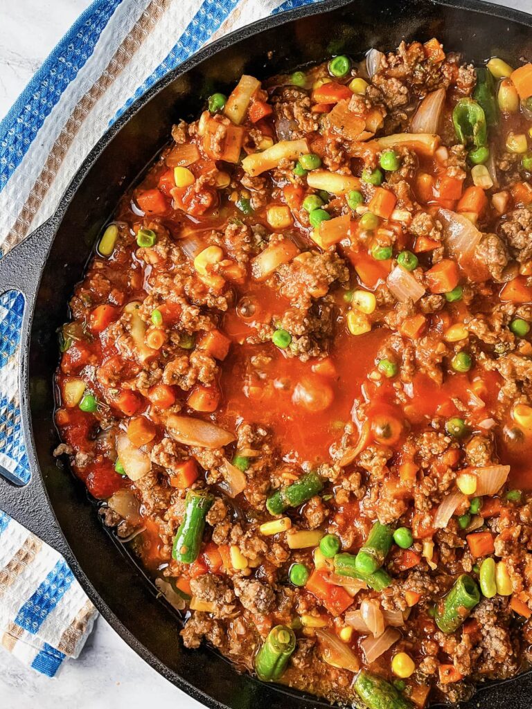 Tomato sauce and meat mixture for Shepherd's Pie in a skillet.