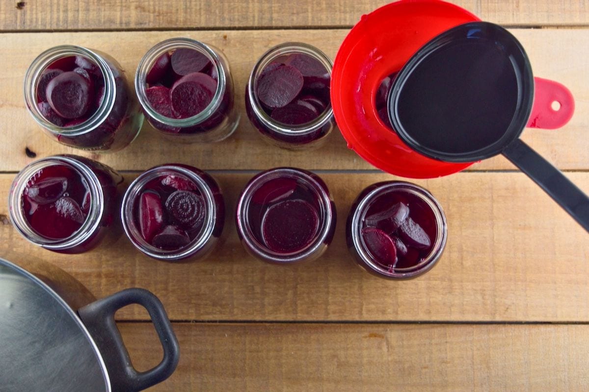 Ladling hot brine over the sliced beets.