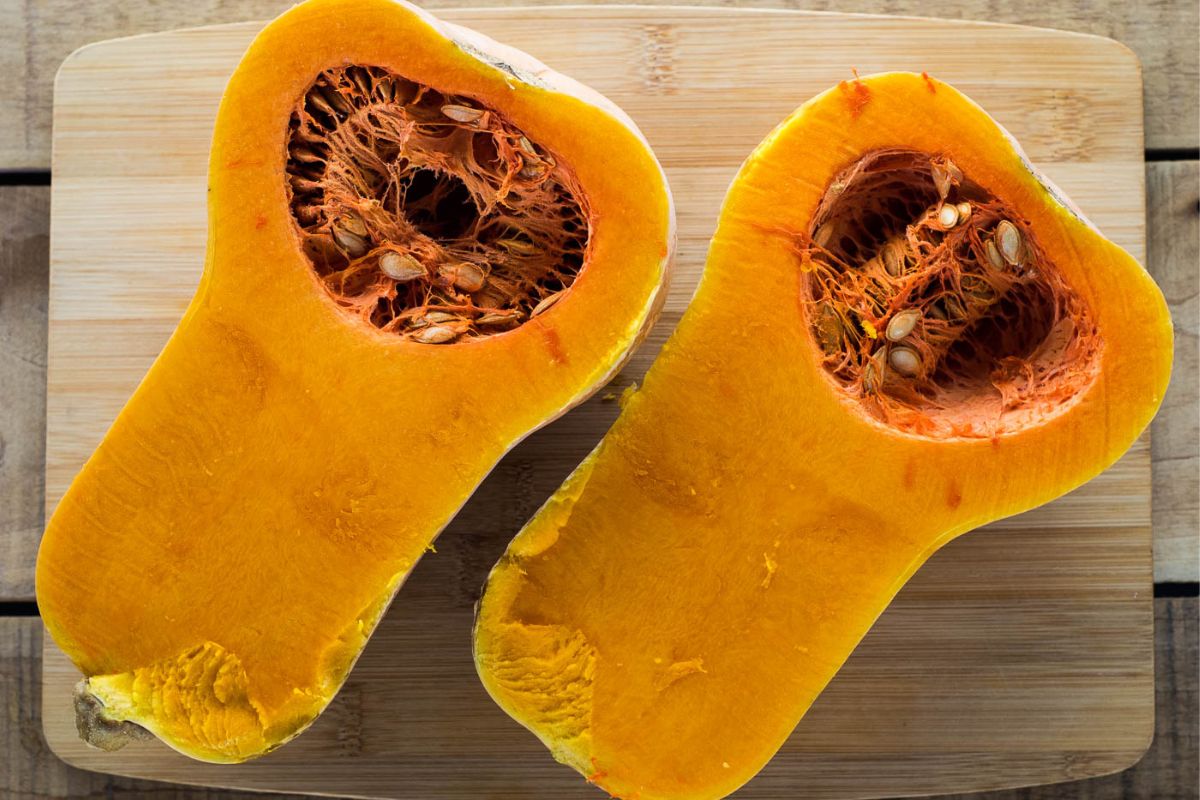 Butternut squash cut in half on a cutting board.