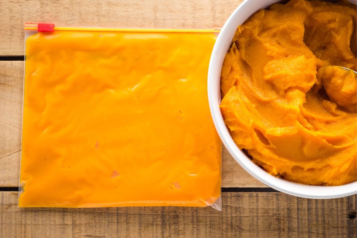Freezer bag with puree laying flat next to a bowl of butternut squash puree.