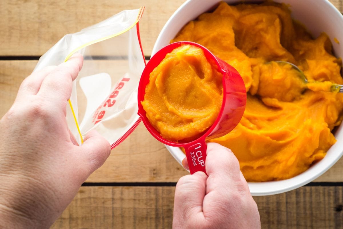 Scooping squash puree into a freezer bag.
