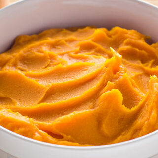 Butternut squash puree ready to serve in a white bowl.