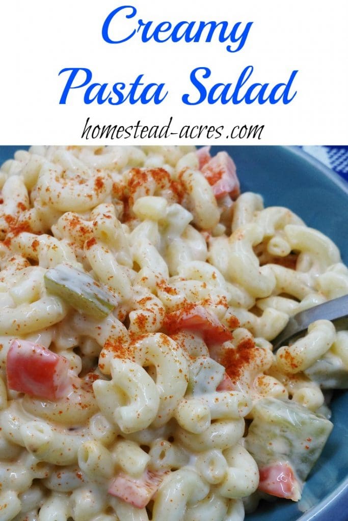 A blue bowl filled with homemade pasta salad. The text overlay says Creamy Pasta Salad.