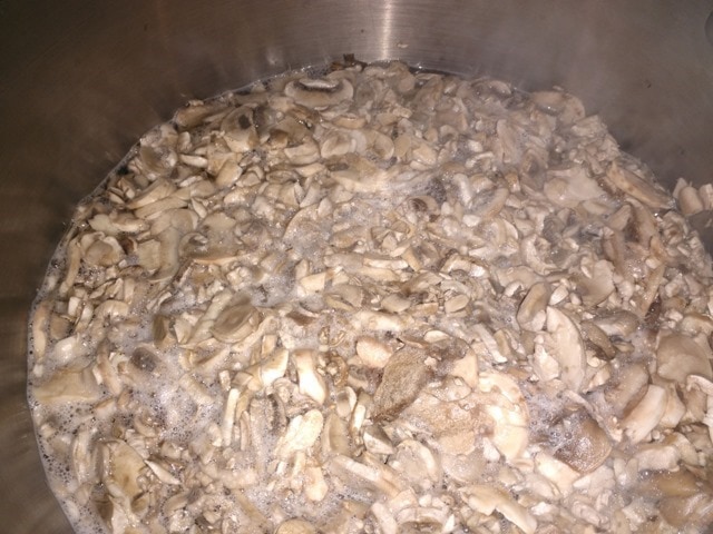 Boiling mushrooms in a large pot.