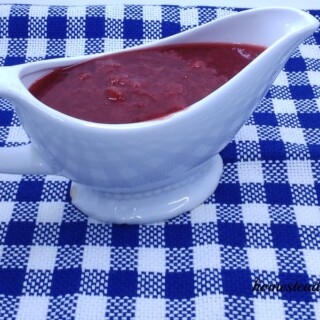 A white serving container filled with homemade strawberry syrup.