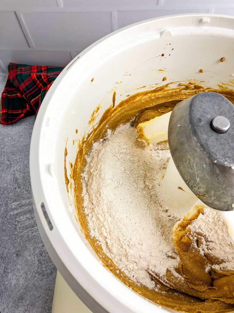 Adding dry ingredients to the wet ingredients in a mixer bowl.
