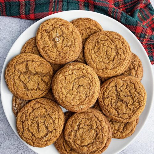 Soft and chewy ginger molasses cookies on a white serving plate.