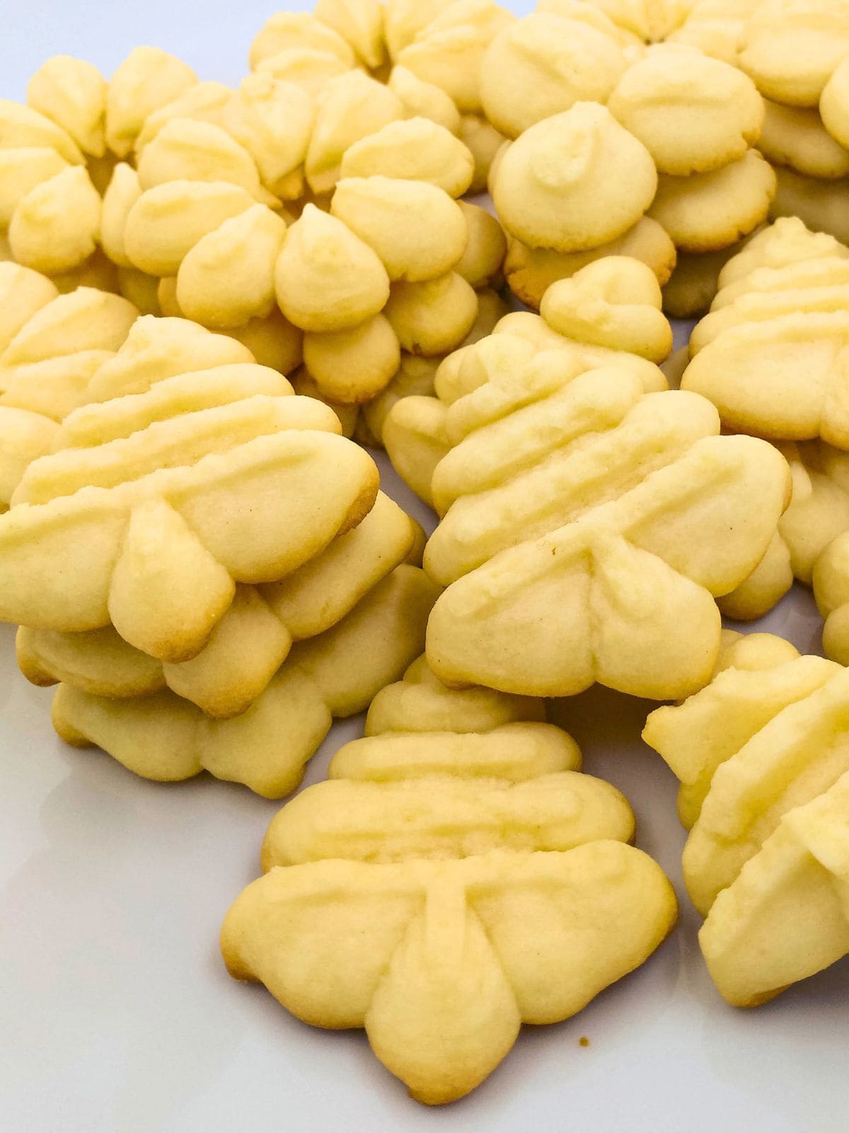 Spritz cookie press cookies shaped like trees and flowers on a serving plate.