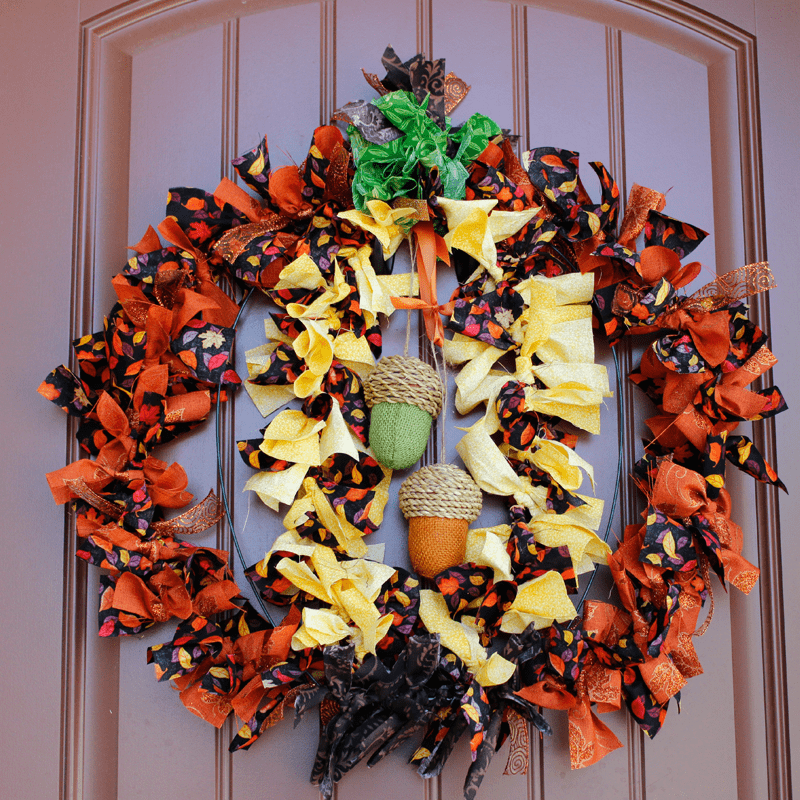 Orange, yellow and black fall wreath with acorns and ribbon.