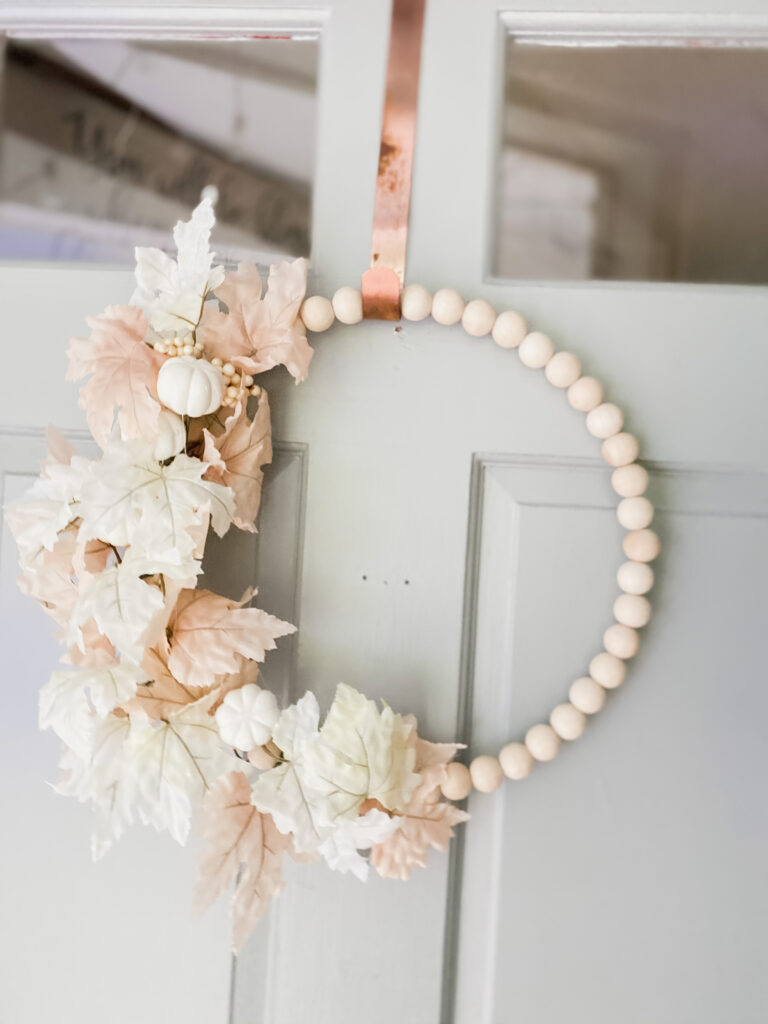 Simple homemade wooden bead wreath with white and light pink fall leaves.