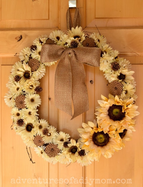 Homemade pinecone and yellow flower wreath with a burlap ribbon.