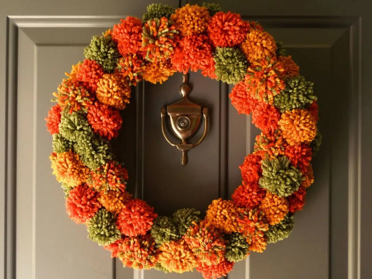 Fall pom pom wreath hanging on a door.