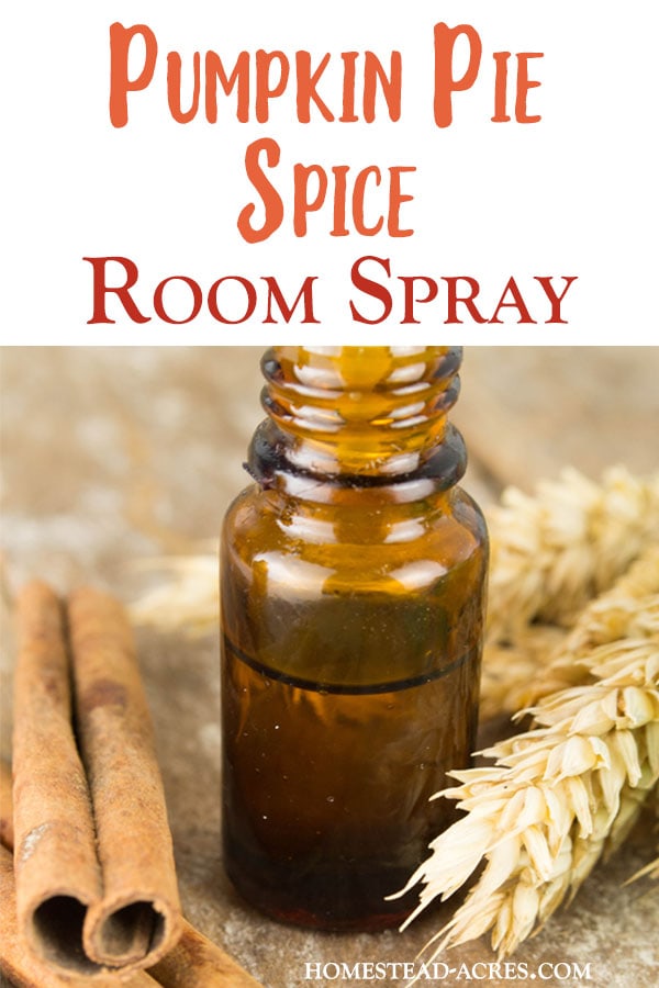 A small dark glass bottle sitting next to cinnamon sticks and wheat on a table. The text overlay says Pumpkin Pie Spice Room Spray.