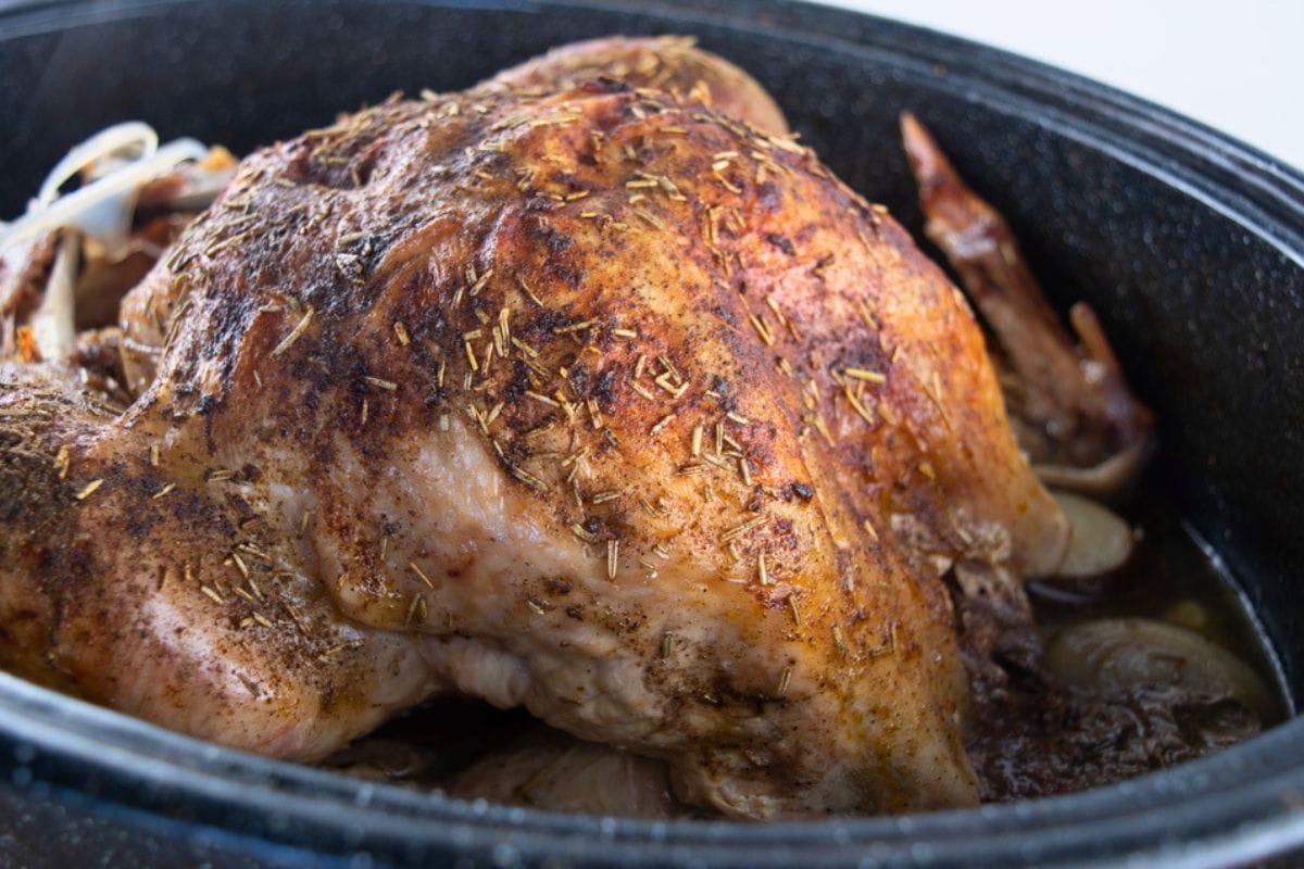 A partially cooked turkey is removed from the oven to be basted.