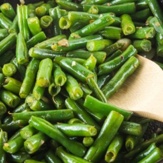 Garlic green beans cooking in a cast iron skillet.
