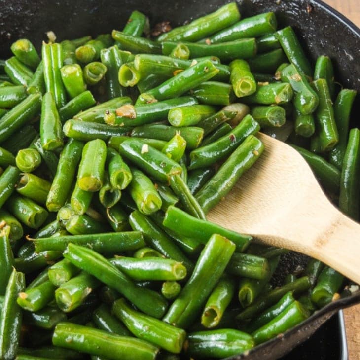 A cast iron frying pan filled with homemade garlic green beans.
