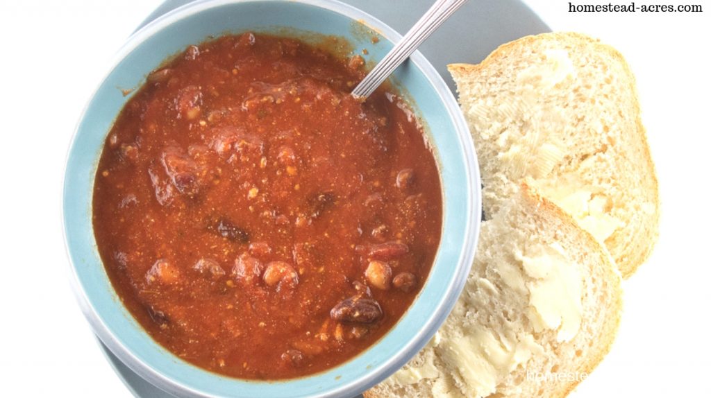Bowl of homemade beef chili with homemade bread on the side.