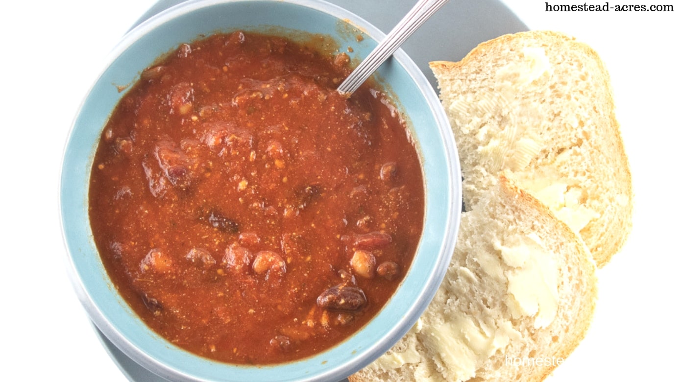 Bowl of homemade beef chili with homemade bread on the side.