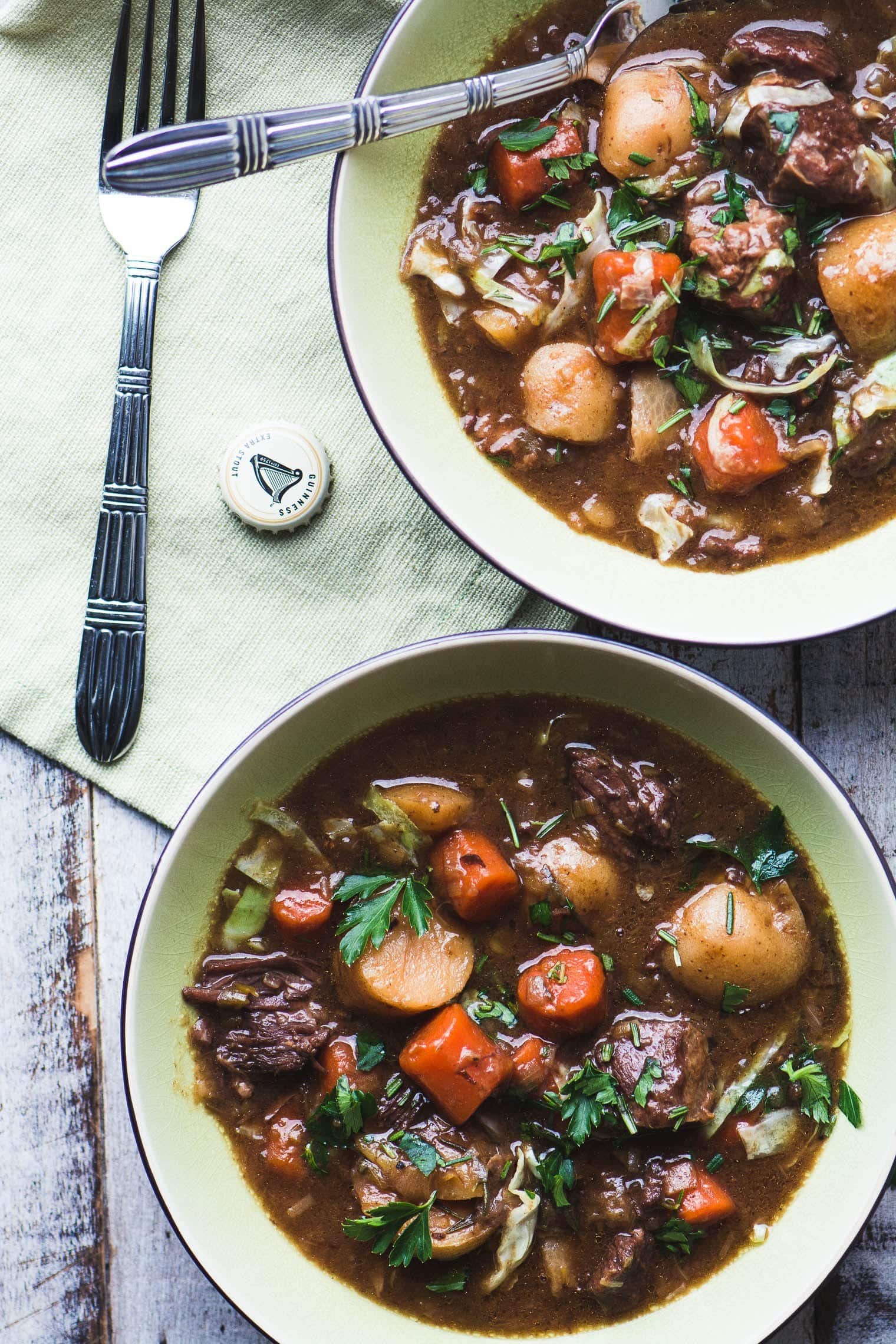 Two bowls of Irish stew sitting on a wooden table.