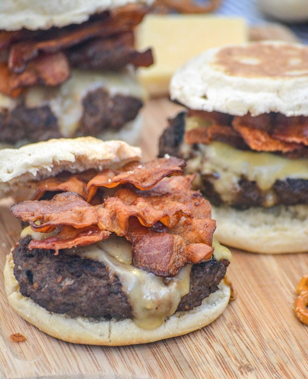 Guinness Irish cheeseburgers with bacon on a wooden cutting board.