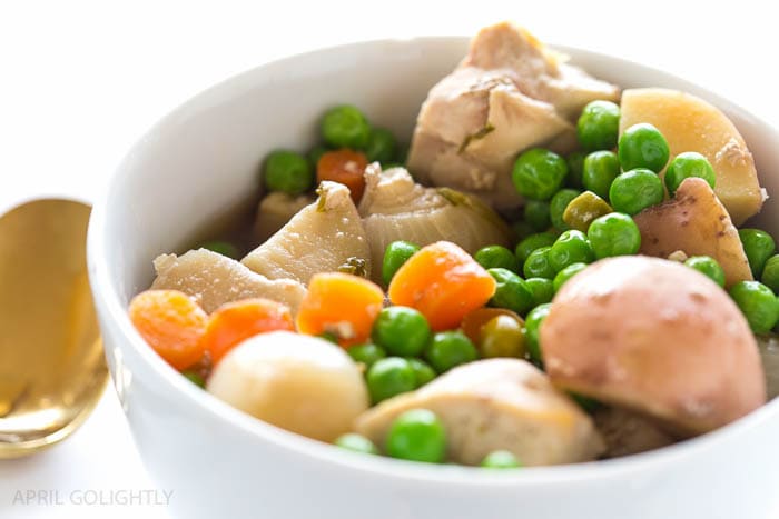 Irish stew with potatoes, onions, carrots, and peas in a white bowl.