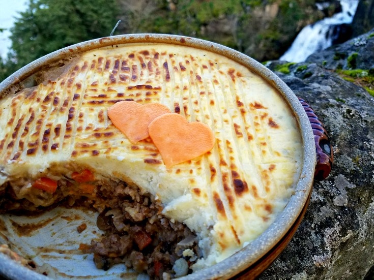 Shepherds pie in a tin baking pan sitting on a rock ledge.