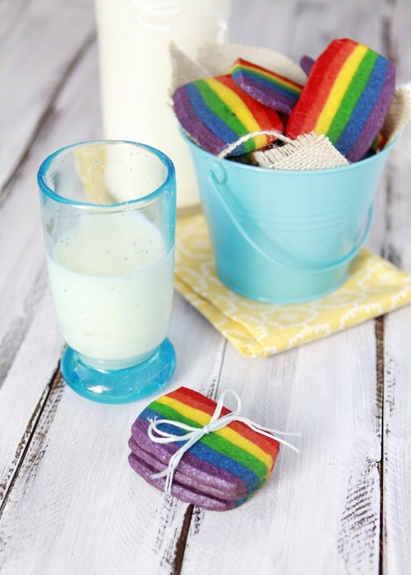 Rainbow cookies for St Patrick's Day on a wooden table next to a glass of milk.