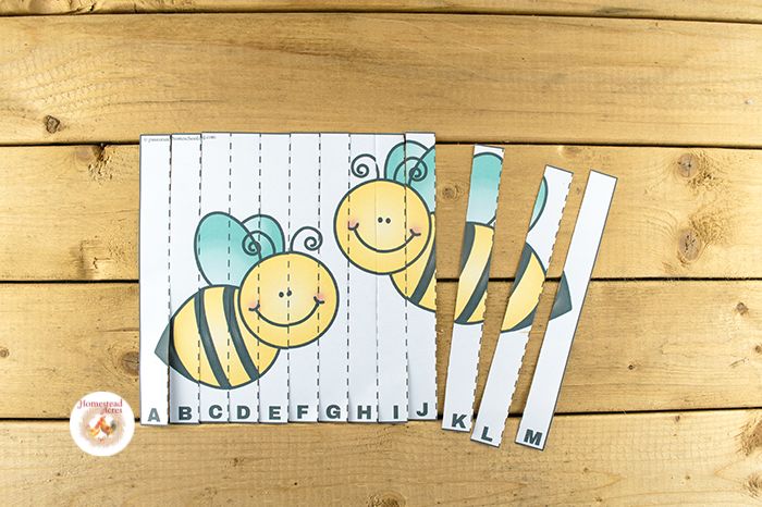 Smiling bees alphabet letter puzzle on a wooden table.