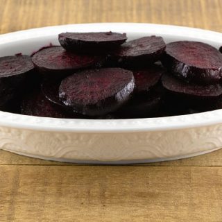 A white serving tray of homemade roasted beets sliced.