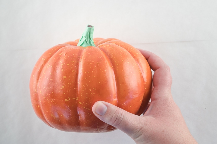 Orange plastic pumpkin from the dollar store with its stem wrapped in painters tape.