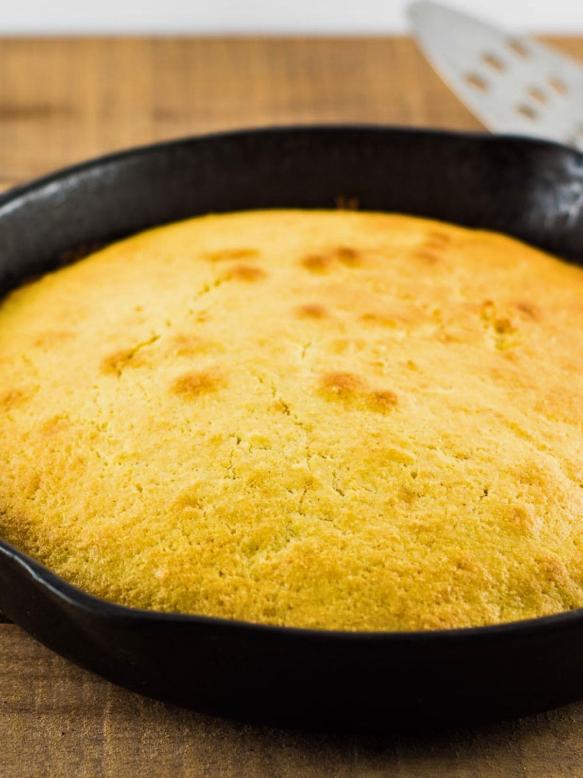 Golden skillet cornbread baked in a black cast iron pan with a lightly browned top and rustic texture. This skillet cornbread recipe without buttermilk is shown fresh from the oven and ready to serve.