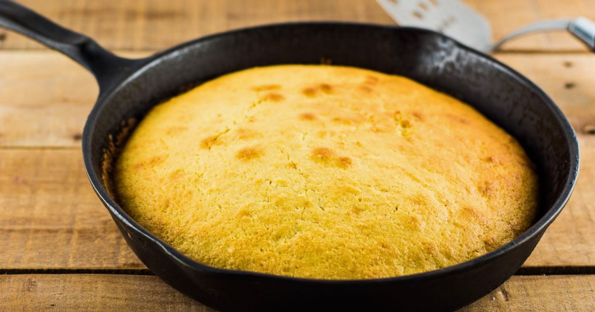 Cornbread in a cast iron skillet on a wooden table.