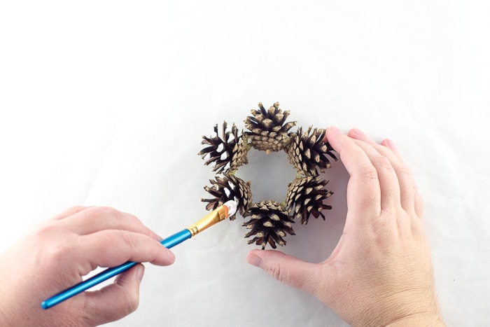 Dotting the ends of the pinecones with white paint to make them look like snow.