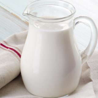 How To Freeze Milk - milk jug filled with fresh milk sitting on a wooden counter