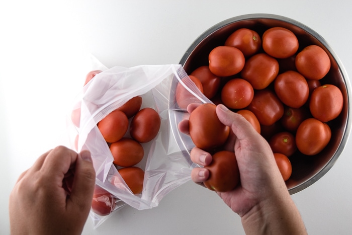 Placing tomatoes into a large freezer bag.