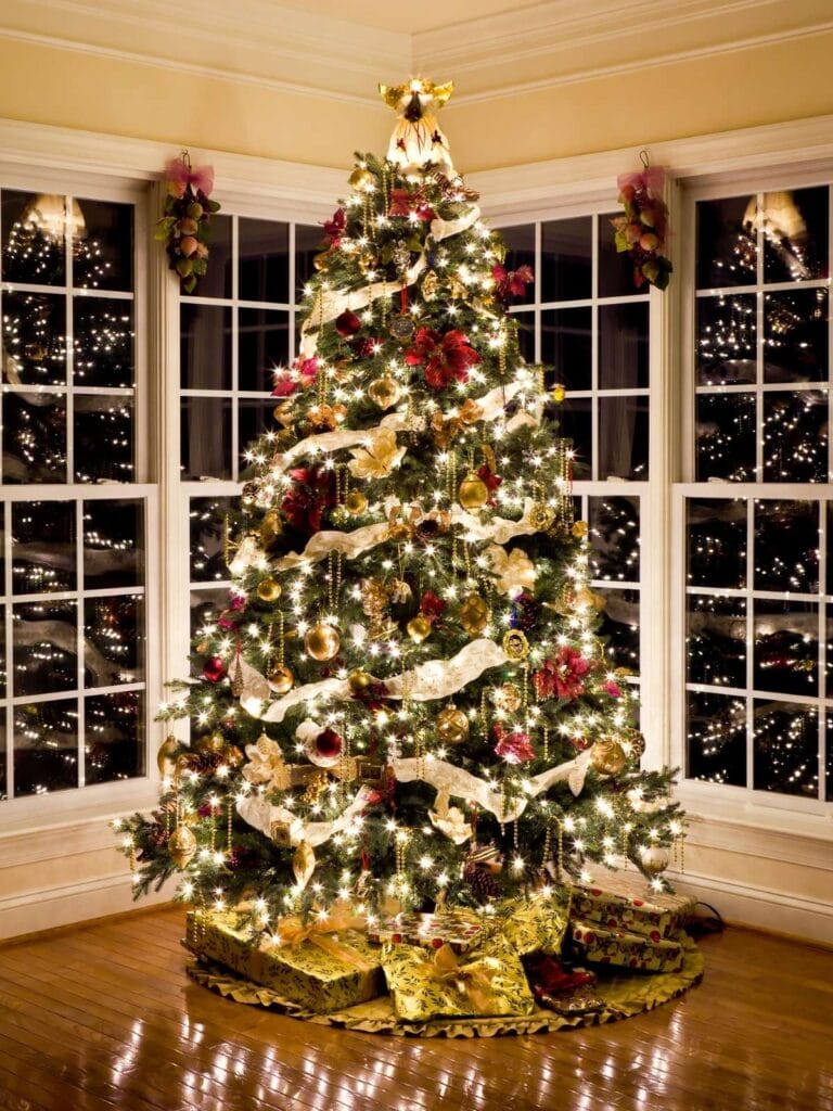 Beautiful real Christmas tree decorated in front of windows.