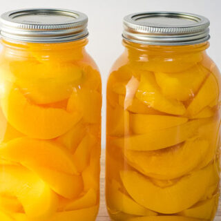 2 jars of home canned peaches on a table.