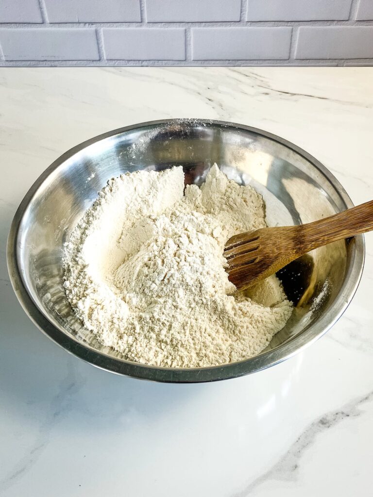 A medium sized mixing bowl filled with dry ingredients for the cobbler topping.