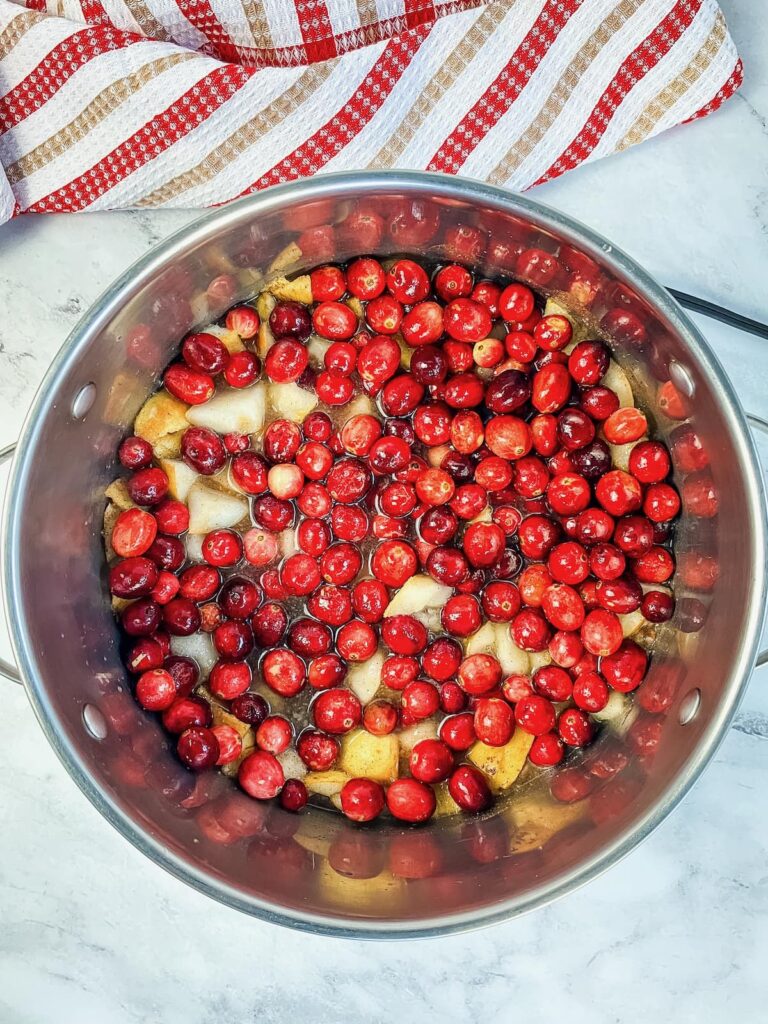 A saucepan with whole cranberries and diced pears cooking.