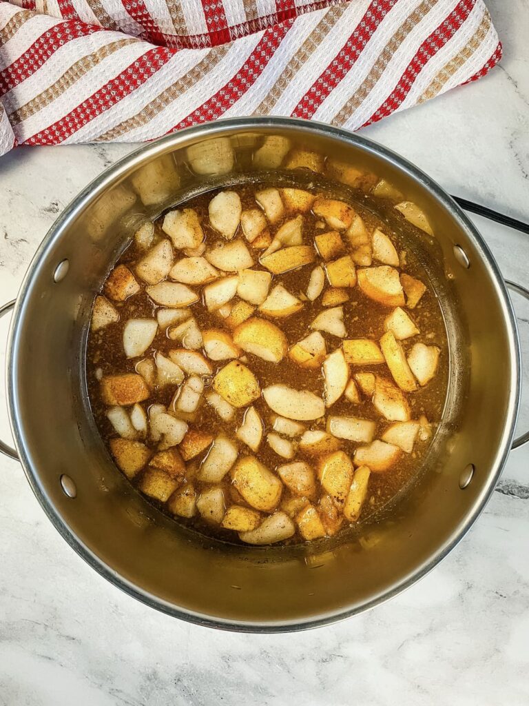 A saucepan with pears, cinnamon, and sugar cooking.