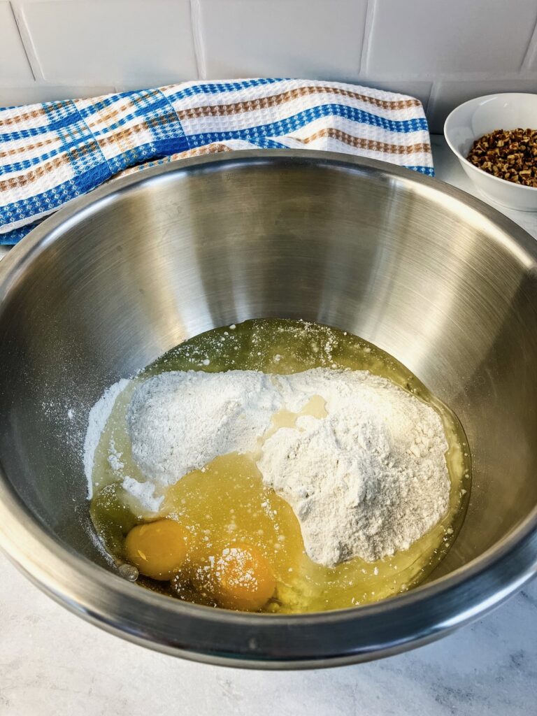 A large mixing bowl with cake mix batter, eggs, and oil.