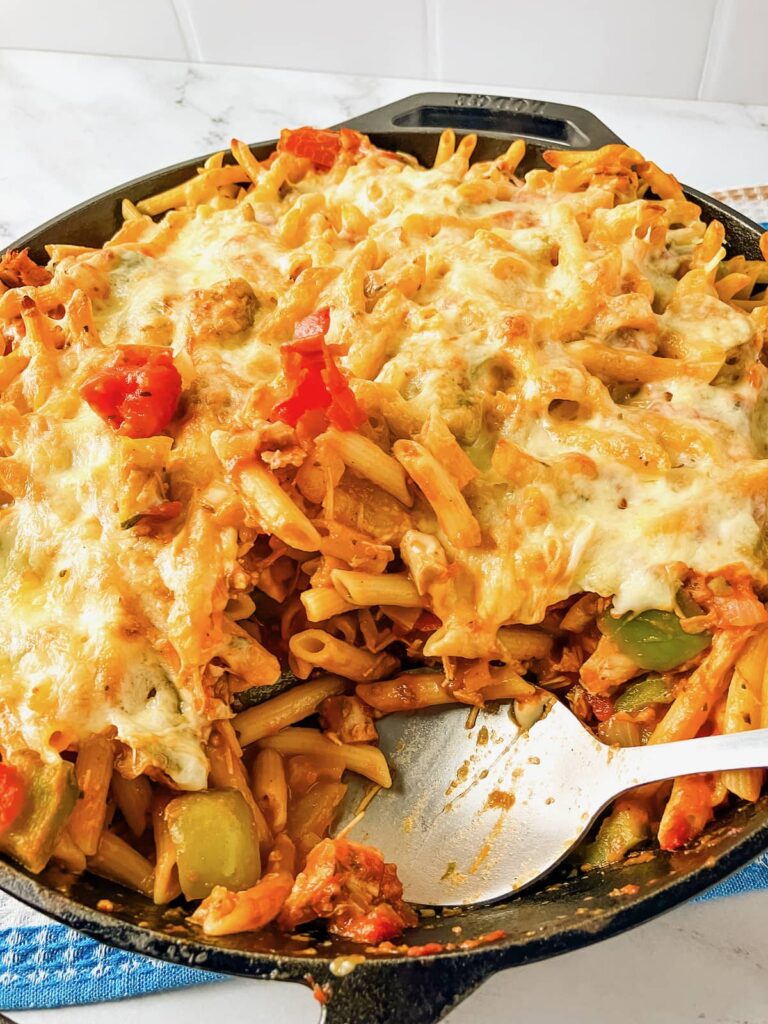 Turkey pasta bake in a skillet with a serving removed and a serving spoon in the pan.