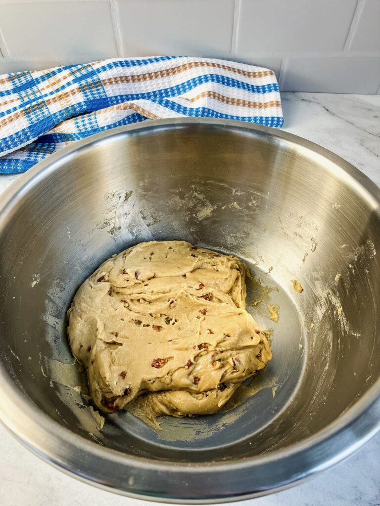 Butter pecan cookie dough with pecan pieces folded into it.